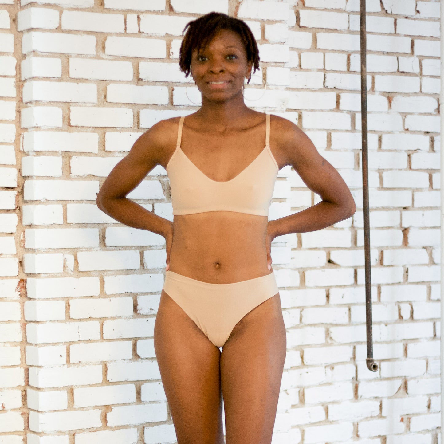 Person wearing beige bra and underwear in a room.